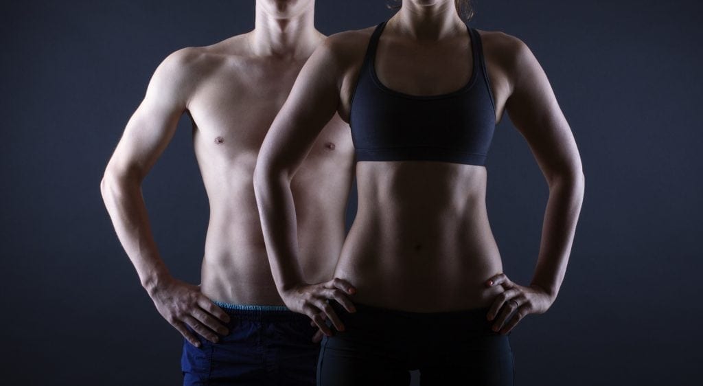 Strong man and a woman posing on a black background