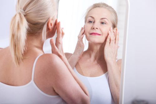 middle aged woman looking at wrinkles in mirror-img-blog