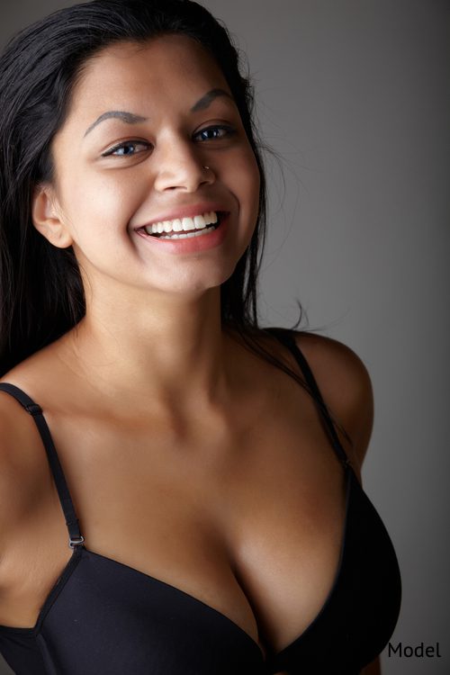 Happy women wearing black bra on gray background. Breast surgery concept.