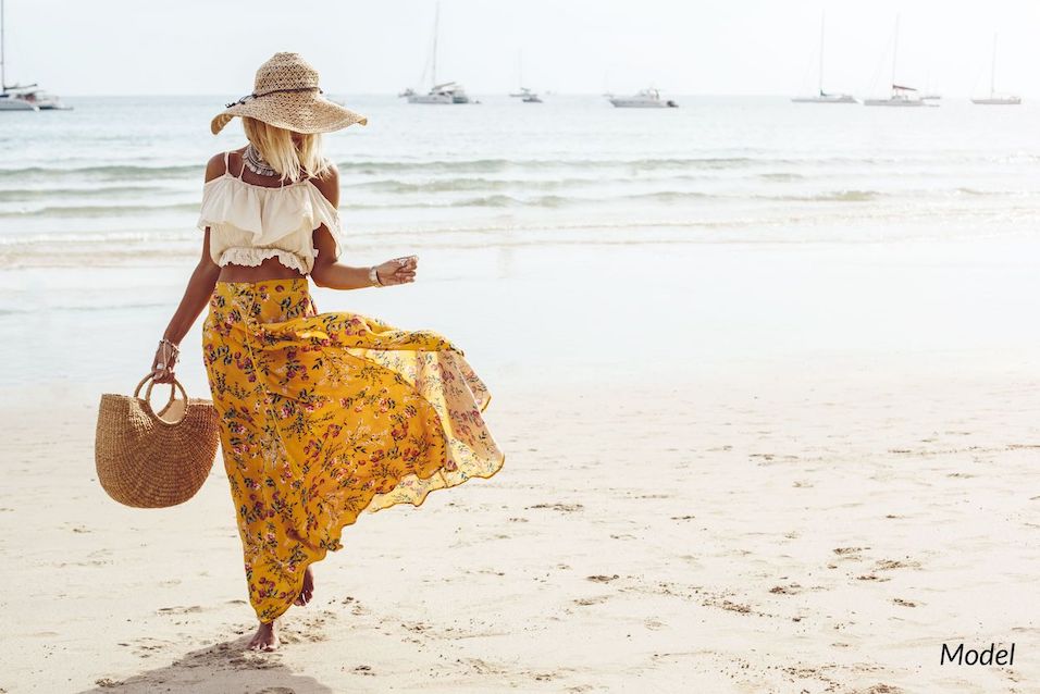 Woman walking on beach as someone can do after a tummy tuck.