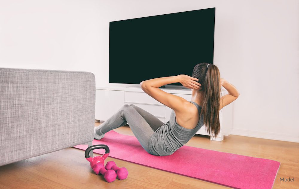 Woman exercising at home, potentially after plastic surgery.