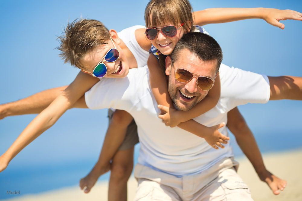  Fit father spending times with his kids on the beach.