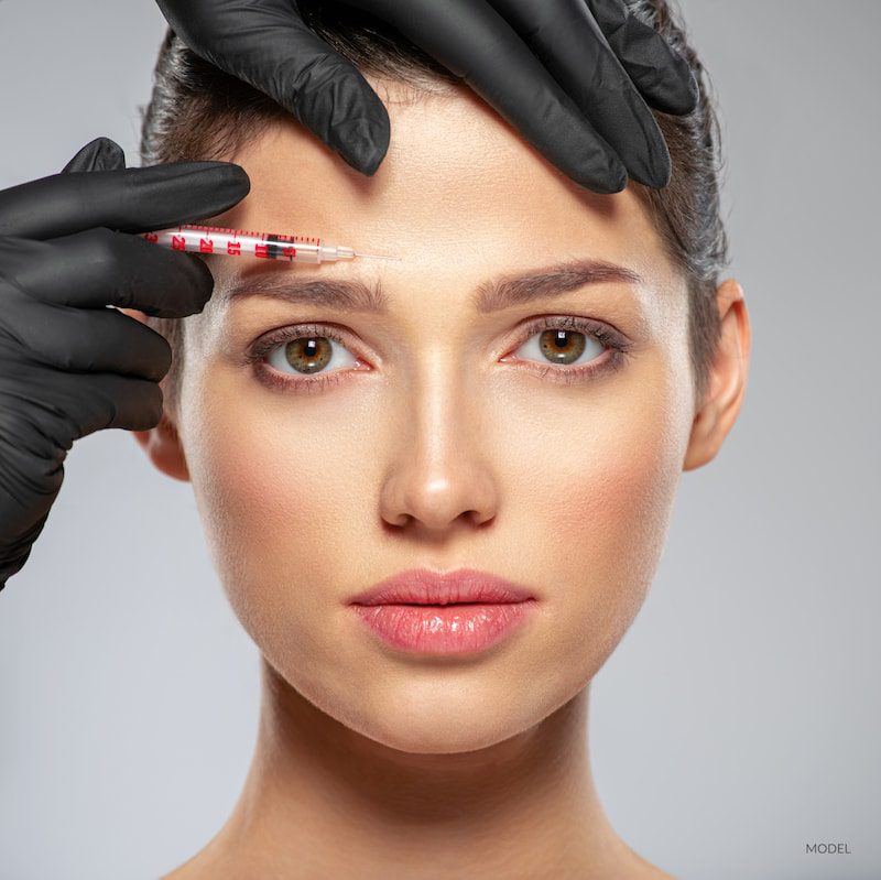 A young women getting a BOTOX® Cosmetic injection with her plastic surgeon.