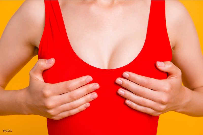  woman lifting up breasts to imitate breast lift