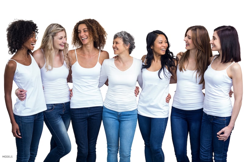 Group of happy multi-ethnic women standing in a line, wearing white-t-shirts.