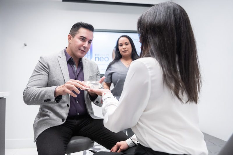 Dr. Careaga showing a breast implant to a female patient.