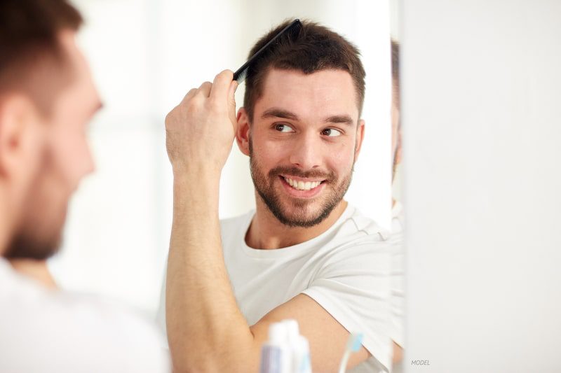 Man combing his hair, looking in mirror