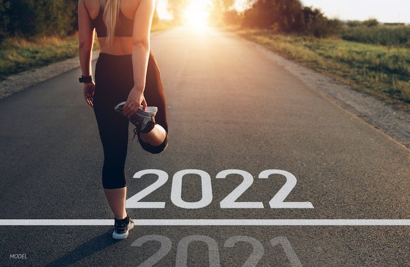 Fit woman stretching at a starting line saying 2022