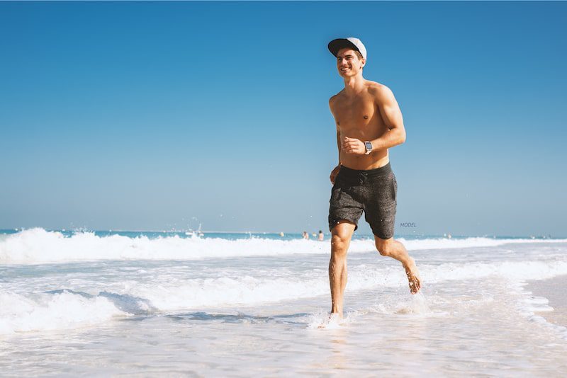 Man running shirtless on the beach