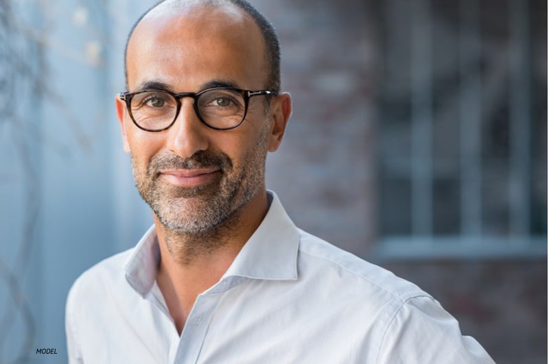 Close-up of middle-aged man's face wearing glasses with a stubble beard.