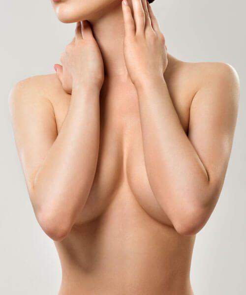 Torso of a naked woman covering her breasts with her forearms