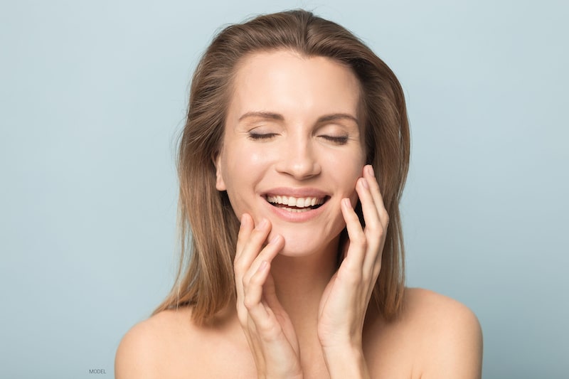 Beautiful woman smiling while she touches the sides of her face