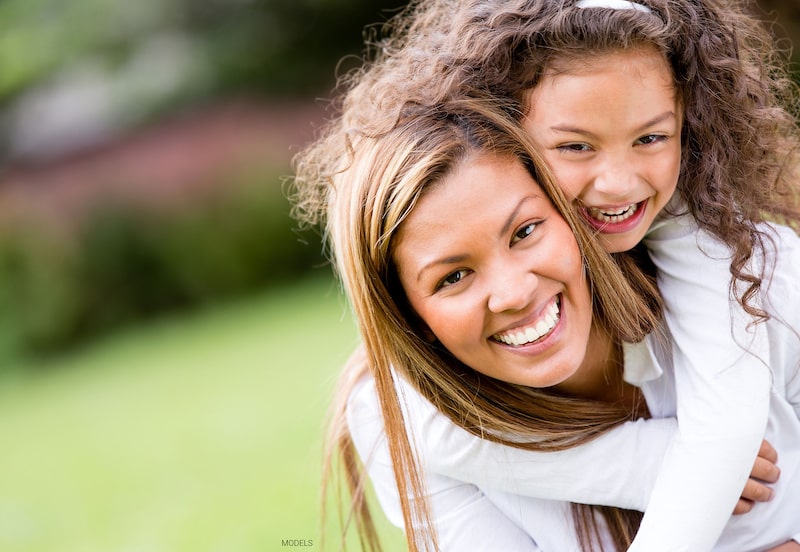 Woman carrying her daughter on her back. 