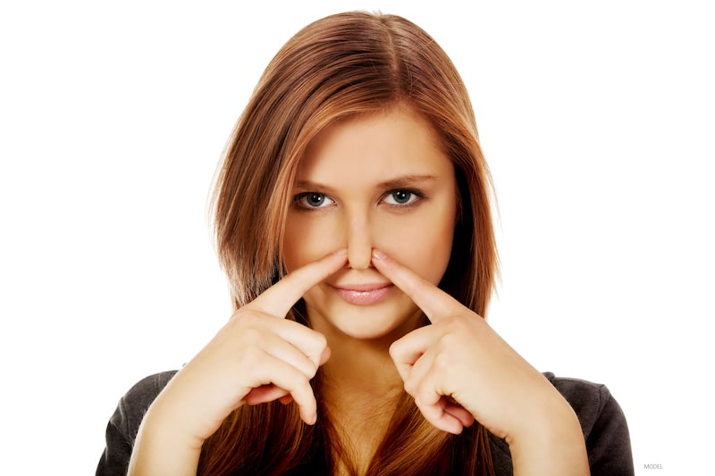Beautiful woman pinching her nose with two fingers
