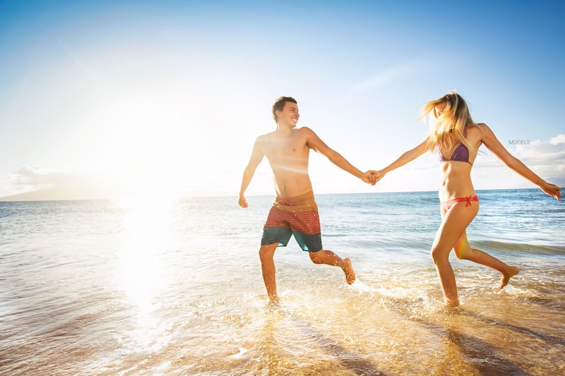 Man and woman running along a beautiful beach