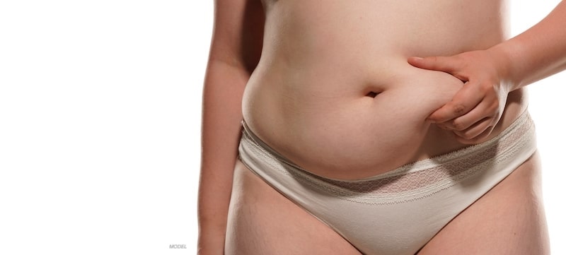 Woman in underwear squeezing excess skin and fat in her belly