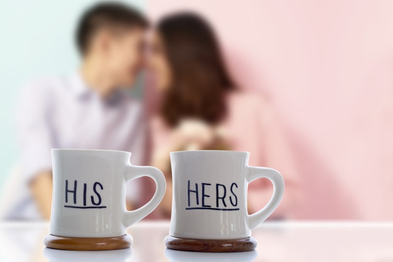 His and hers mugs with a blurred couple behind them. 