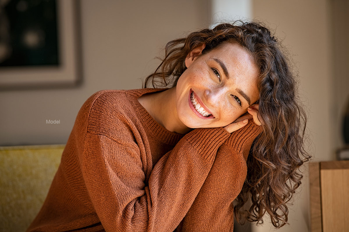 A happy woman in a brown sweater.