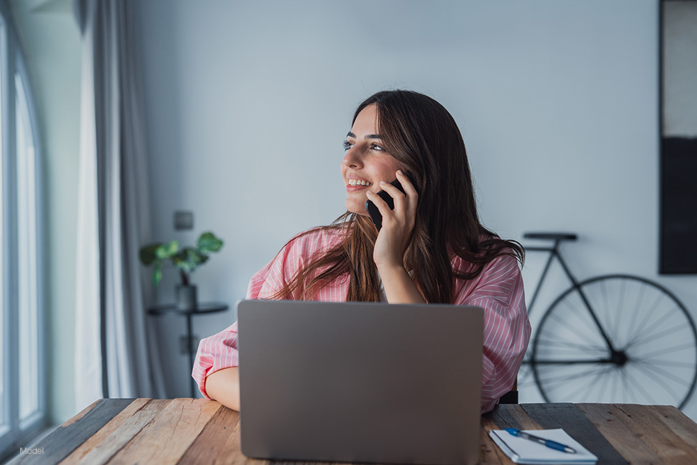 woman sitting at a laptop on the phone